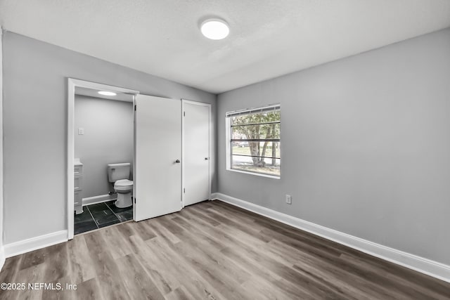 unfurnished bedroom with a closet, baseboards, a textured ceiling, and wood finished floors