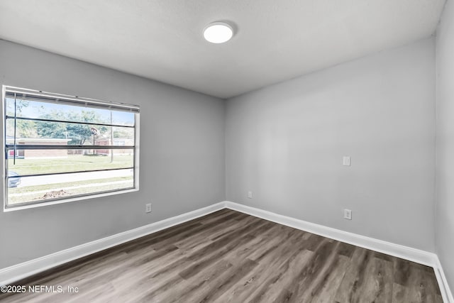 unfurnished room with baseboards and dark wood-type flooring