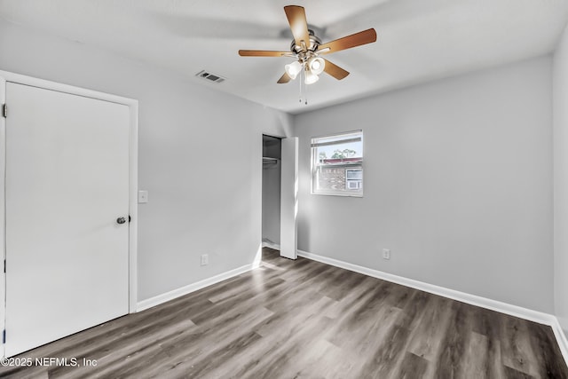 unfurnished bedroom featuring visible vents, baseboards, wood finished floors, a closet, and a ceiling fan