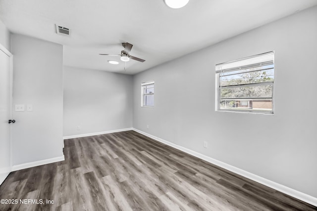 empty room with visible vents, a healthy amount of sunlight, baseboards, and wood finished floors