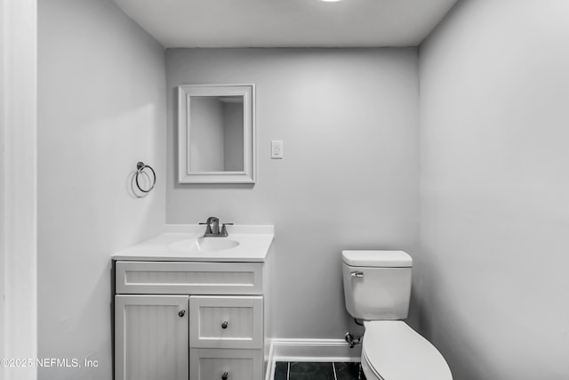 half bathroom with vanity, toilet, and baseboards