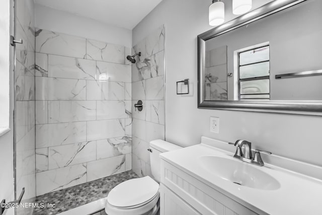 bathroom featuring a tile shower, toilet, and vanity