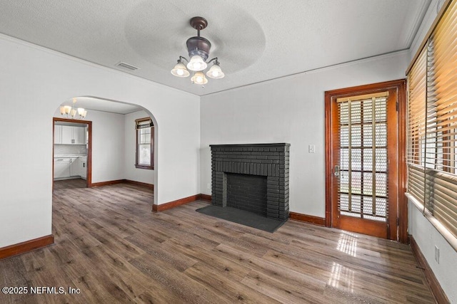 unfurnished living room with a ceiling fan, wood finished floors, visible vents, arched walkways, and a textured ceiling