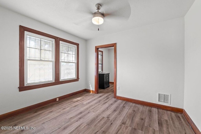 spare room featuring visible vents, ceiling fan, baseboards, and light wood-style floors