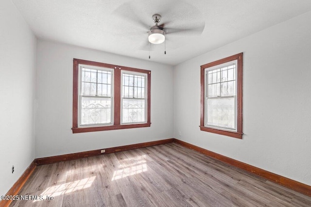 unfurnished room with wood finished floors, baseboards, and ceiling fan