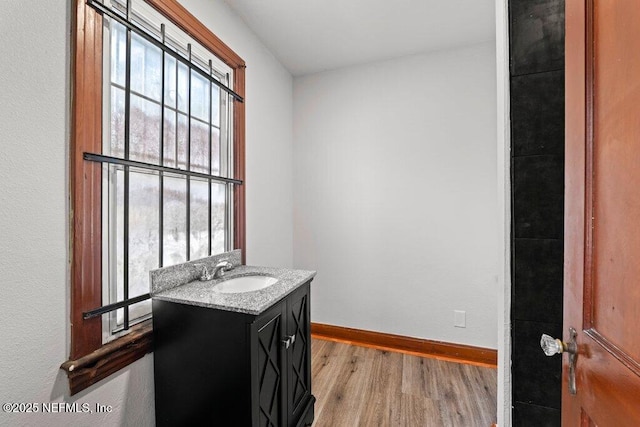 bathroom with baseboards, wood finished floors, and vanity