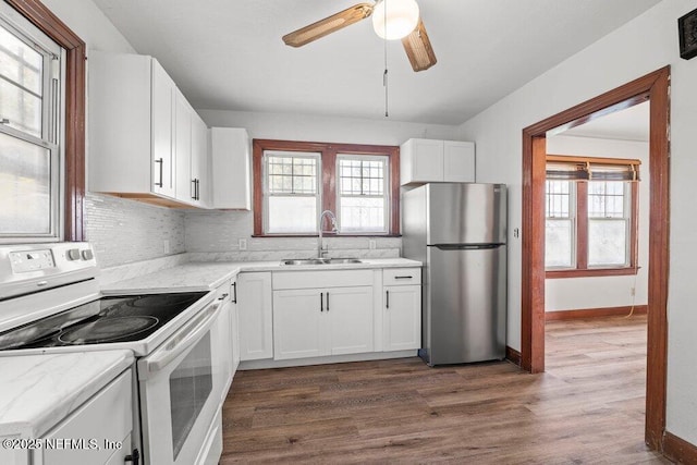 kitchen with dark wood finished floors, freestanding refrigerator, electric range, white cabinetry, and a sink