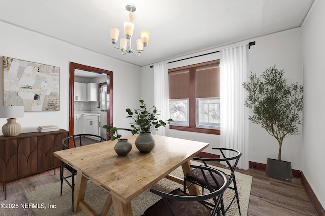 dining area featuring a chandelier, baseboards, and light wood-style flooring