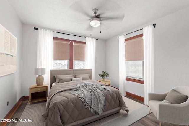 bedroom featuring multiple windows, wood finished floors, and baseboards