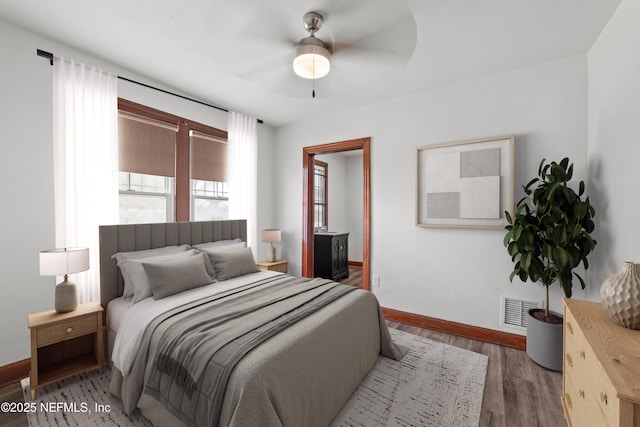 bedroom with visible vents, ceiling fan, baseboards, wood finished floors, and ensuite bath