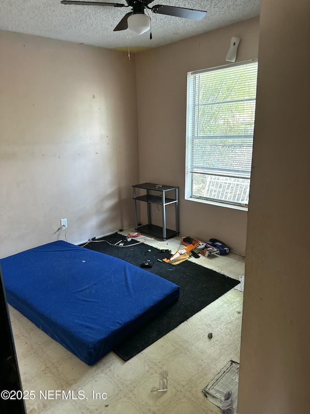 bedroom with a ceiling fan and a textured ceiling