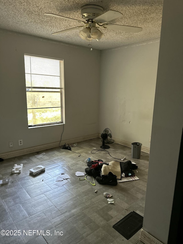 unfurnished room featuring a ceiling fan, baseboards, and a textured ceiling