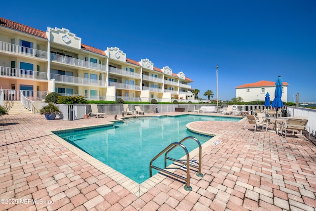 pool with a patio and fence