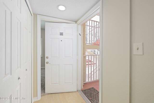 doorway with light wood-style flooring and a textured ceiling