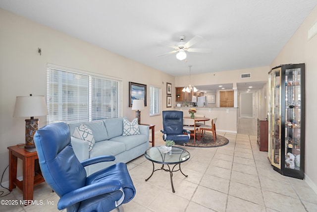 living area with light tile patterned floors, visible vents, ceiling fan with notable chandelier, and baseboards