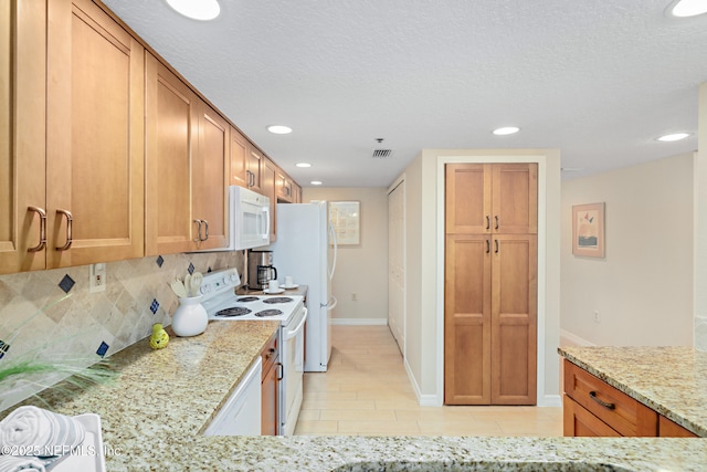 kitchen featuring visible vents, white appliances, backsplash, and light stone countertops