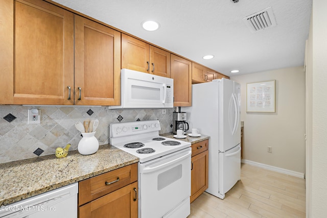 kitchen featuring light wood finished floors, visible vents, baseboards, decorative backsplash, and white appliances