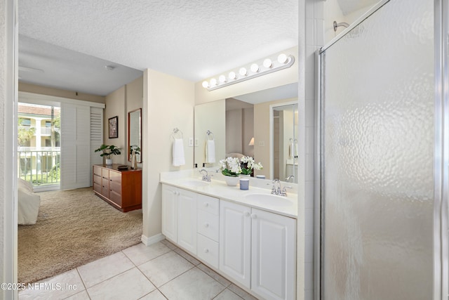 bathroom with tile patterned flooring, a shower stall, a textured ceiling, and a sink