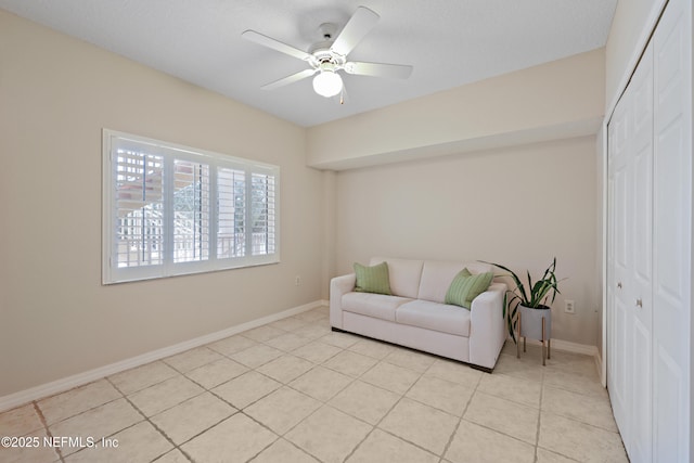 living area featuring light tile patterned floors, baseboards, and a ceiling fan