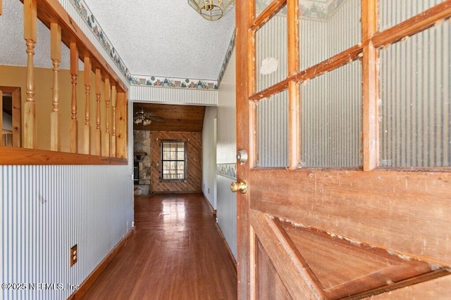 hall with wood finished floors and a textured ceiling