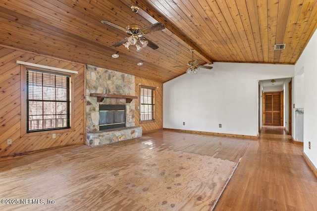 unfurnished living room featuring visible vents, wood walls, lofted ceiling with beams, a fireplace, and wood-type flooring