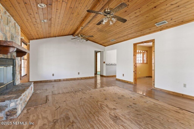 unfurnished living room with visible vents, baseboards, lofted ceiling with beams, hardwood / wood-style floors, and a stone fireplace