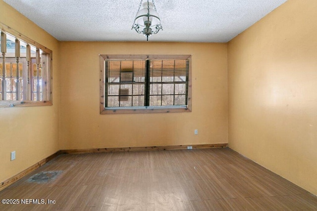 unfurnished room featuring baseboards, a textured ceiling, a healthy amount of sunlight, and wood finished floors