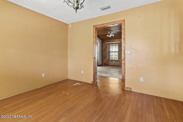 empty room featuring wood finished floors, visible vents, and a textured ceiling