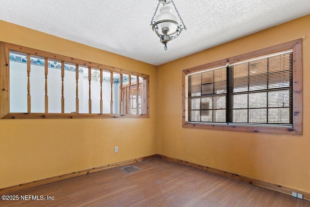 empty room featuring baseboards, a wealth of natural light, and a textured ceiling