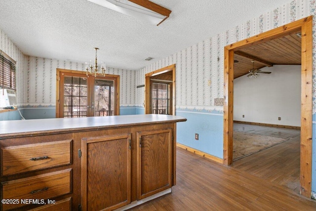 kitchen featuring a wainscoted wall, a textured ceiling, and wallpapered walls