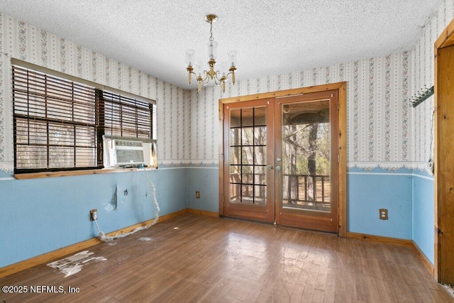 empty room featuring hardwood / wood-style floors, cooling unit, wallpapered walls, wainscoting, and a textured ceiling