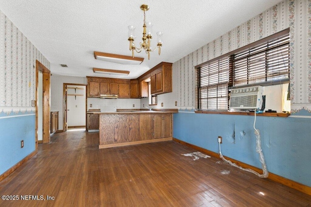 kitchen featuring wallpapered walls, baseboards, under cabinet range hood, a textured ceiling, and dark wood-style flooring