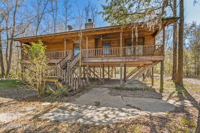 view of front of house featuring stairs, covered porch, and a chimney