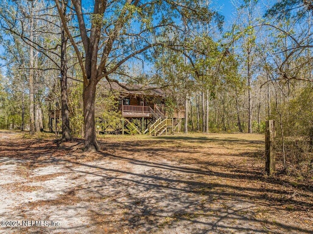 view of yard featuring stairway, a deck, and a wooded view