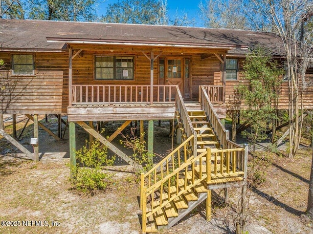 rear view of property with roof with shingles, covered porch, and stairs