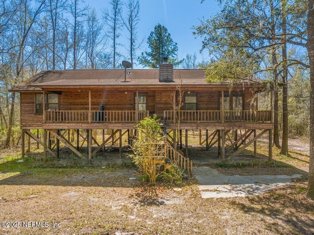 back of property with a porch, stairway, and a chimney