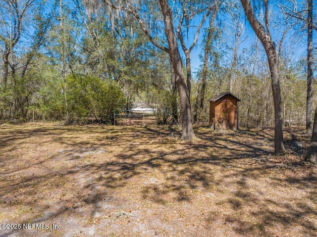 view of yard with a view of trees, an outbuilding, and a shed