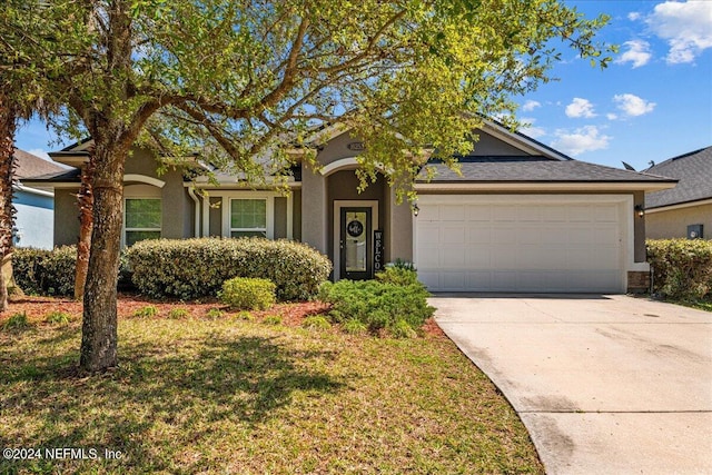 single story home with stucco siding, driveway, a front yard, and a garage