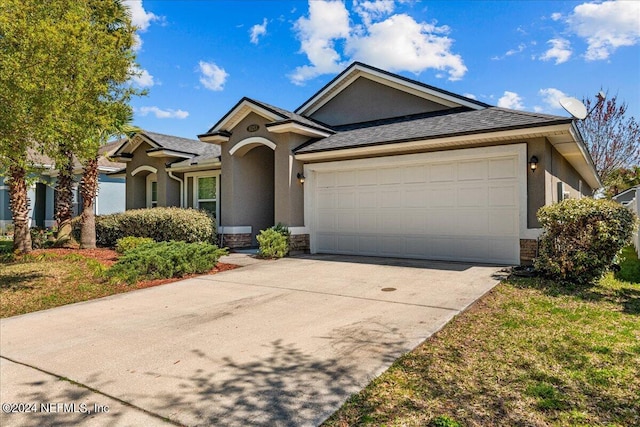 view of front of home featuring stucco siding, driveway, an attached garage, and a shingled roof