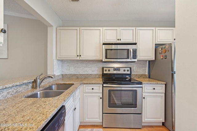 kitchen featuring light stone countertops, tasteful backsplash, appliances with stainless steel finishes, and a sink