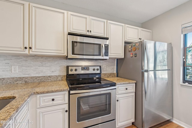 kitchen with decorative backsplash, light stone counters, white cabinetry, and appliances with stainless steel finishes