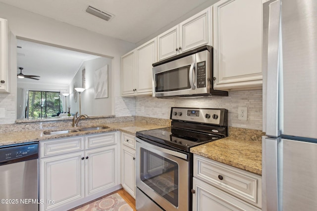 kitchen featuring tasteful backsplash, visible vents, appliances with stainless steel finishes, a ceiling fan, and a sink