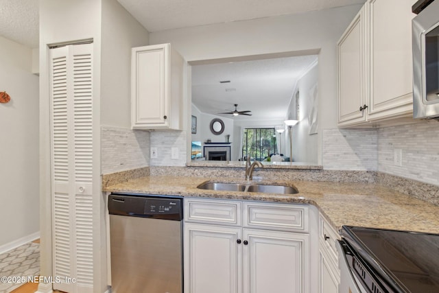 kitchen with light stone countertops, a ceiling fan, a sink, white cabinets, and appliances with stainless steel finishes