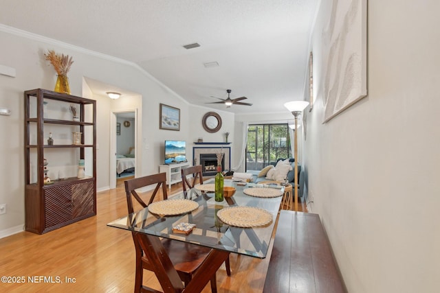 dining space with lofted ceiling, ceiling fan, crown molding, and light wood finished floors