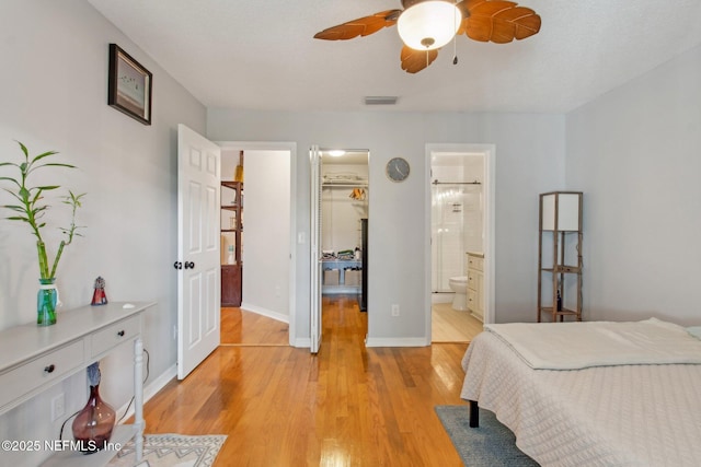 bedroom with a walk in closet, visible vents, a closet, light wood finished floors, and baseboards