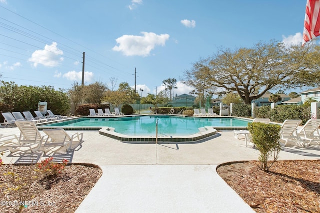 pool with a patio area and fence