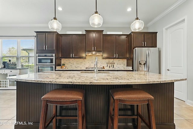 kitchen with light tile patterned floors, a sink, stainless steel appliances, crown molding, and backsplash