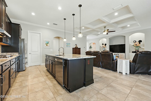 kitchen with a sink, open floor plan, stainless steel appliances, arched walkways, and light stone countertops