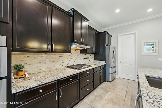 kitchen featuring under cabinet range hood, ornamental molding, light stone counters, decorative backsplash, and stainless steel appliances