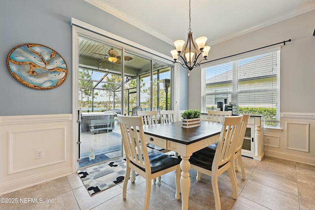 dining space featuring crown molding, a chandelier, wainscoting, a sunroom, and a decorative wall